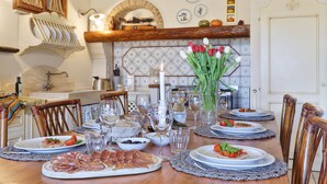 A dining table set with plates, glasses, and a vase of flowers.