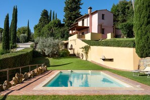 A residential property with a swimming pool, a stone pathway, and a well-maintained garden.