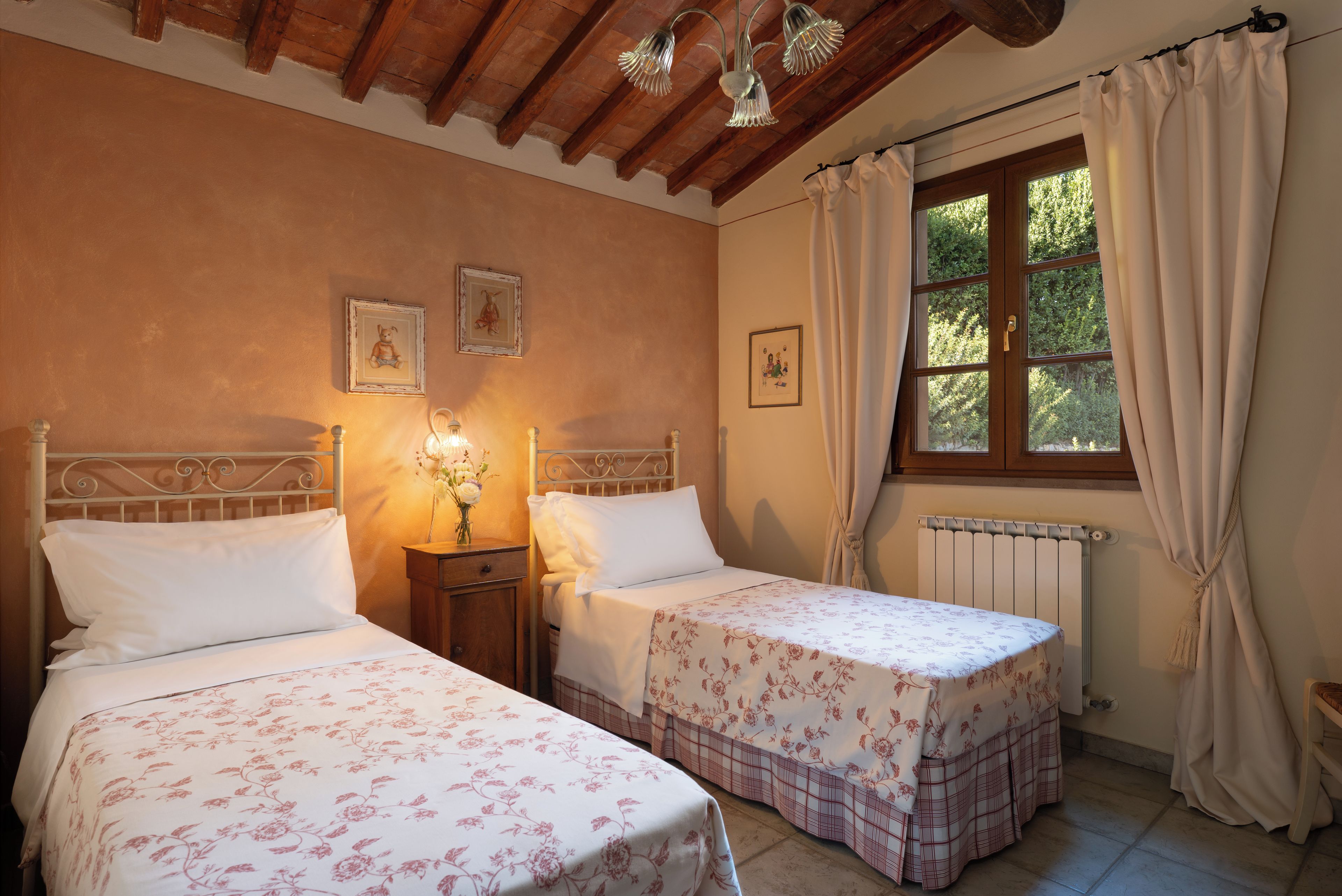 A room with two beds, a window with curtains, and a radiator.
