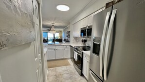 Una cocina moderna con electrodomésticos de acero inoxidable, armarios blancos y una isla grande.