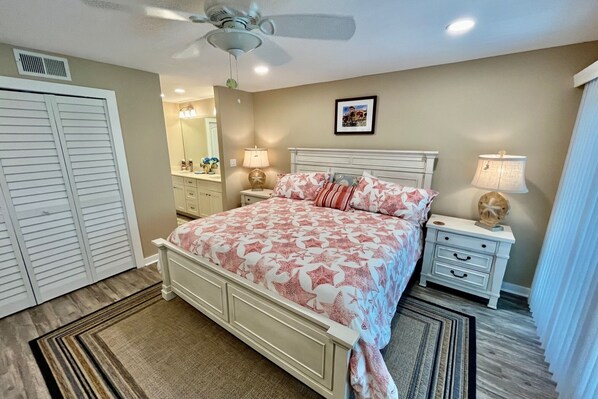 A bedroom with a bed, nightstands, a ceiling fan, a mirror, and a picture on the wall.