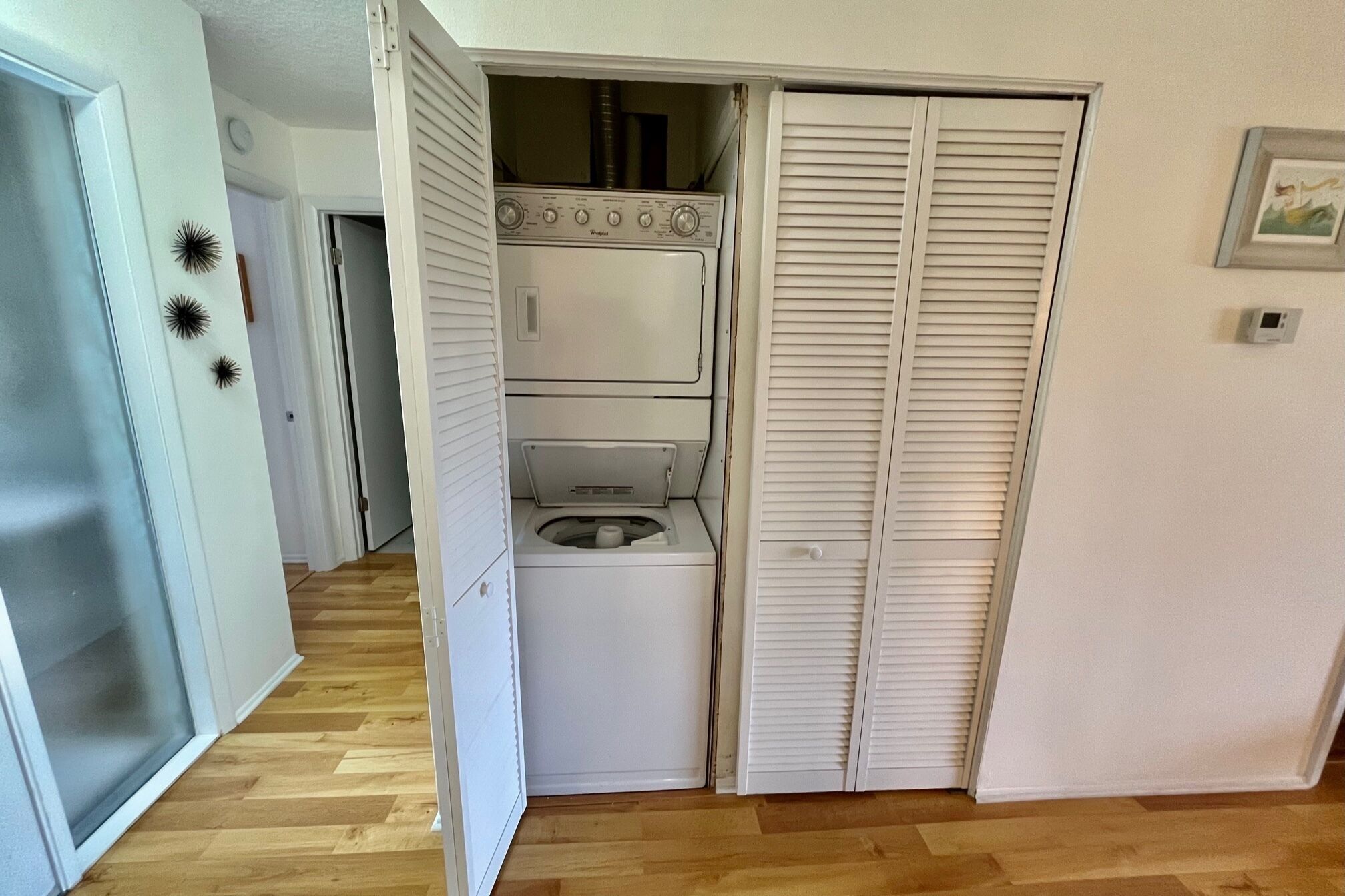 A compact laundry room with a washer and dryer, a small window, and a door leading to another room.