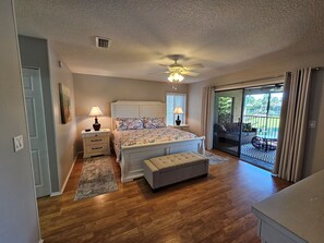 A bedroom with a bed, bedside tables, a ceiling fan, a window, and a sliding glass door leading to an outdoor area. - VDL 75 - Relax and enjoy the tranquil lagoon in this 2nd floor condo. (Saint Augustine)