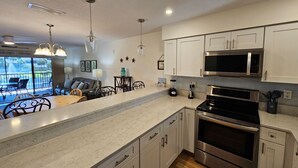 Una cocina moderna con armarios blancos, electrodomésticos de acero inoxidable y encimera de mármol.