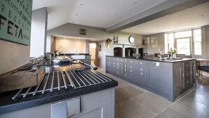 Une cuisine spacieuse dotée d’un grand îlot central, de meubles modernes et bénéficiant d’un éclairage naturel abondant grâce à de grandes fenêtres.