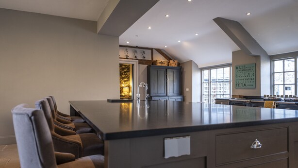 Une cuisine moderne dotée d’un grand îlot central, de meubles de rangement intégrés et d’un coin repas avec des chaises.