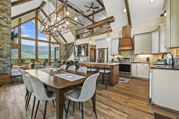 A spacious kitchen with a large island, wooden beams, and a view of the mountains.
