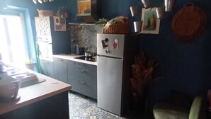 A kitchen with a patterned floor, a refrigerator, and a dining area with a table and chairs.