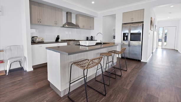 A modern kitchen with a central island, stainless steel appliances, and a bar stool seating area.