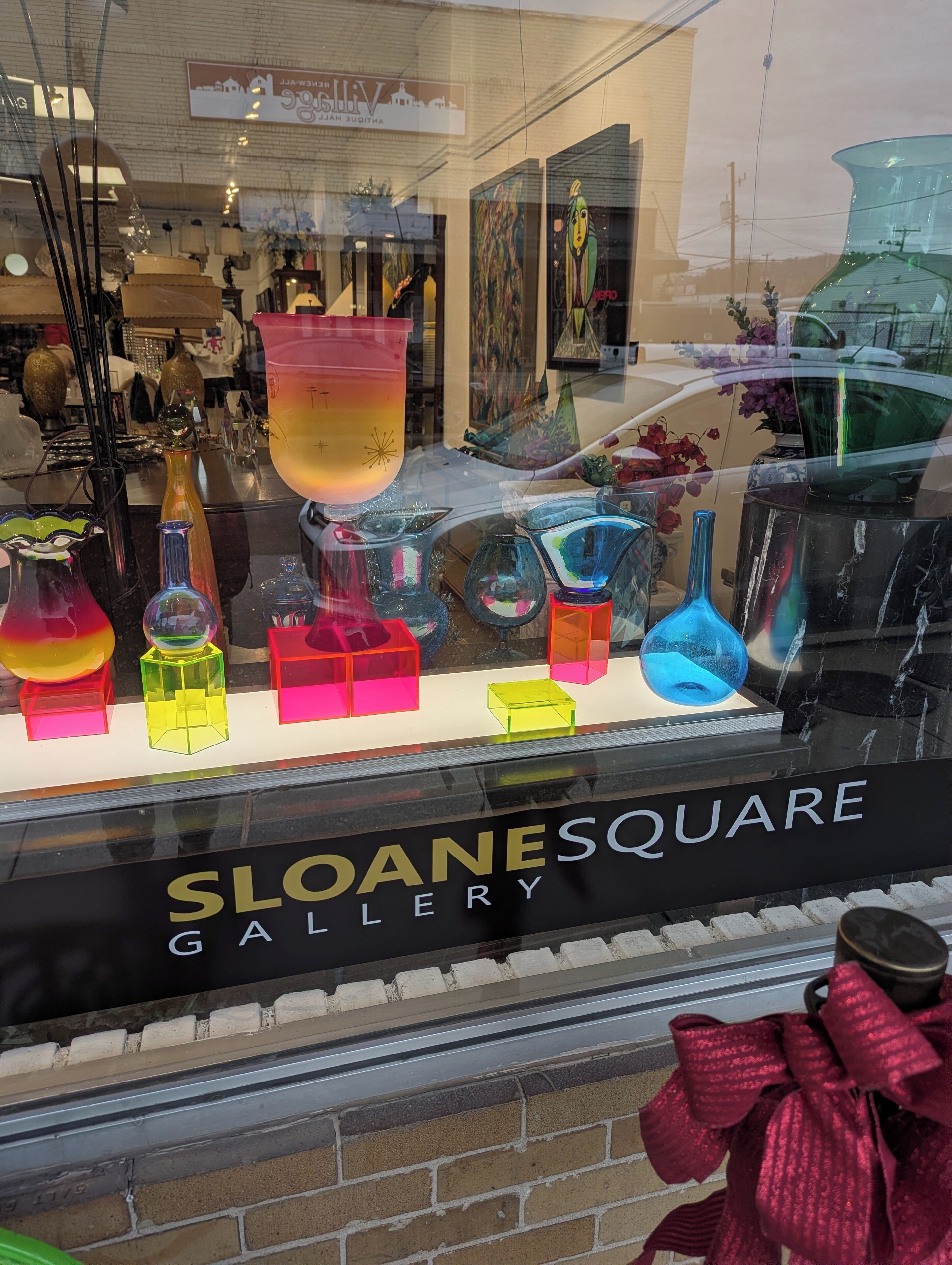 A gallery window with colorful glassware and sculptures.