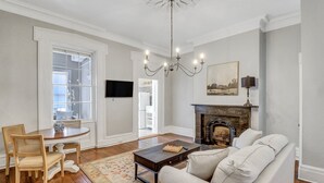 Ein Wohnzimmer mit Kamin, einer Couch, einem Couchtisch, einem Fernseher und einer Chandelier.
