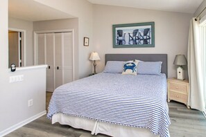 A bedroom with a bed, a nightstand, a lamp, a picture on the wall, and a door.