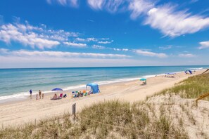 Una playa con cielo despejado, orilla arenosa y algunas personas.