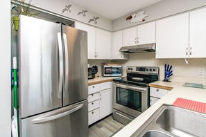 A modern kitchen with stainless steel appliances, white cabinets, and a built-in oven.