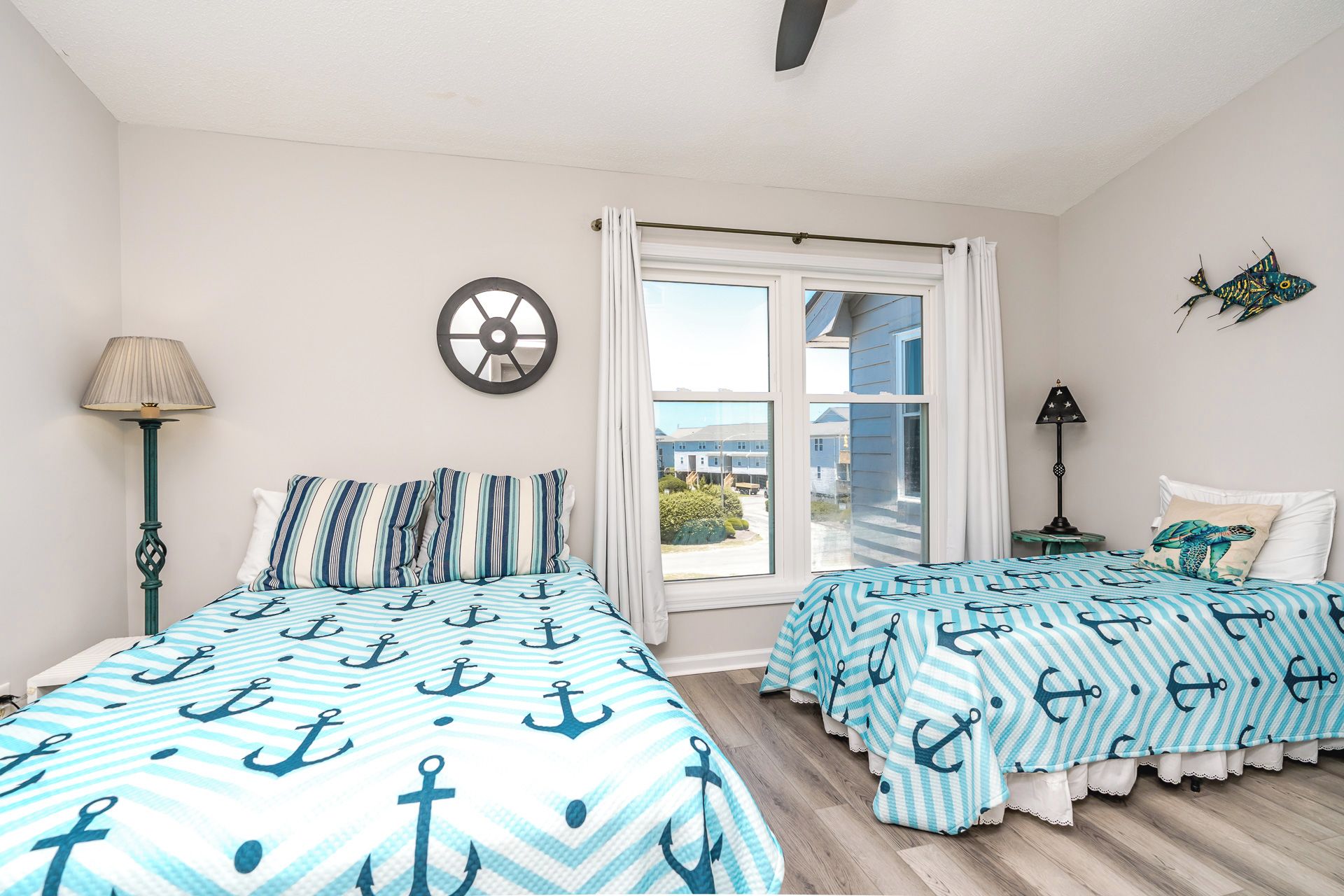 Quarto com duas camas, janela, relógio de parede e vista para o exterior.