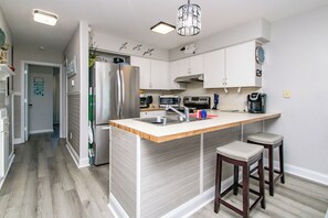 Een moderne keuken met een centraal eiland, roestvrijstalen apparatuur en een hanglamp.
