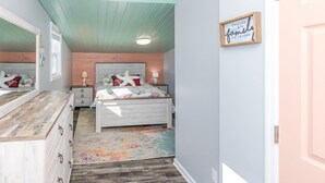 A bedroom with a bed, bedside tables, a dresser, a mirror, and a wall with a framed sign. - Duzzi's Destiny - Oceanfront 5 BR Cottage!  Dog Friendly! (Surf City)