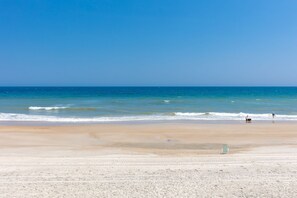 A beach with a clear sky, calm sea, and a few people. - Duzzi's Destiny - Oceanfront 5 BR Cottage!  Dog Friendly! (Surf City)