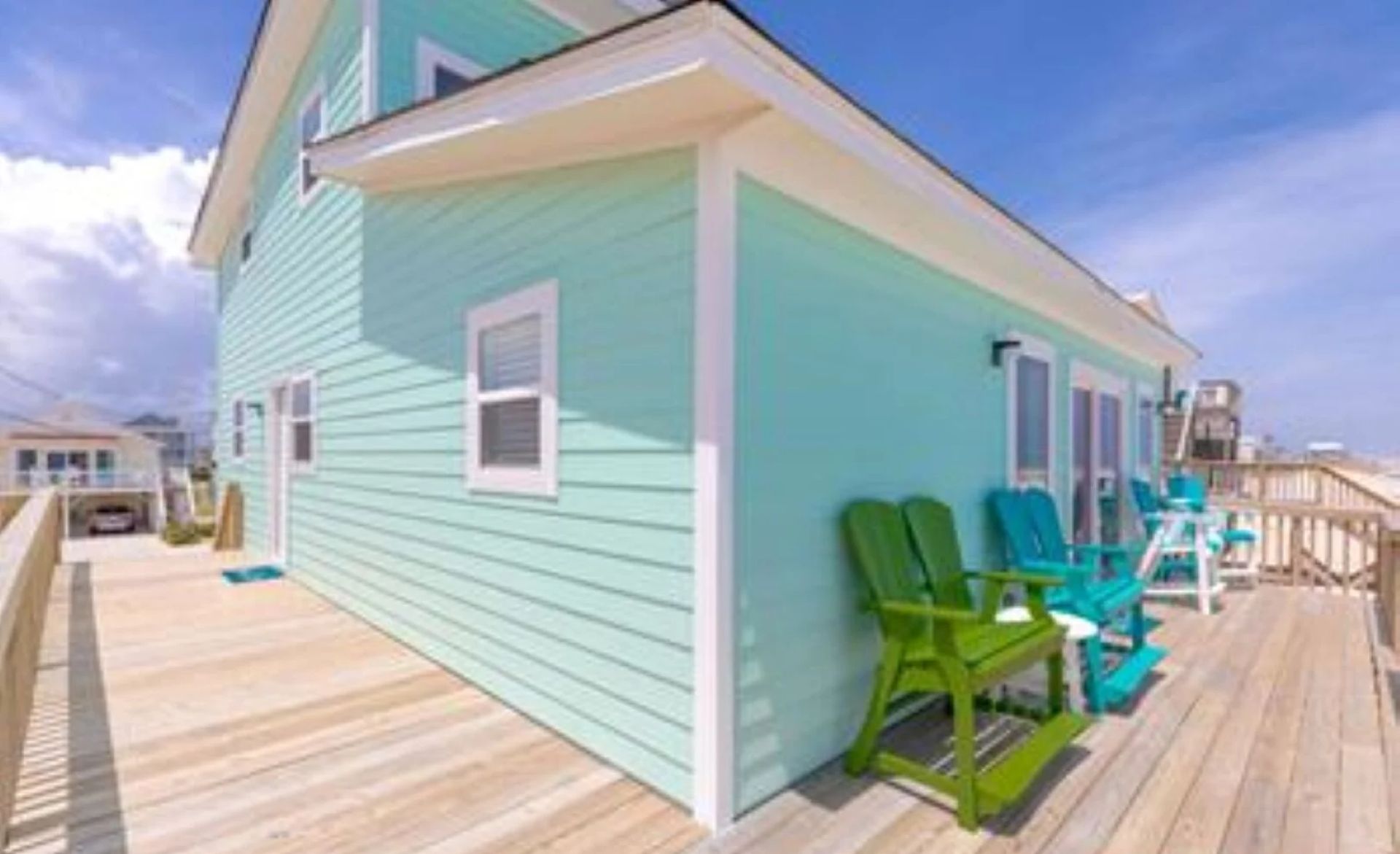A coastal house with a wooden deck, a covered porch, and a view of the ocean.