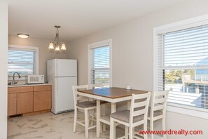 Compact kitchen area with a refrigerator, microwave, and sink, adjacent to a dining space with a table and chairs.