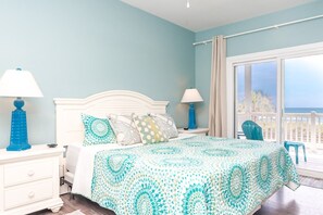 Une chambre à coucher avec un lit, deux tables de chevet, une fenêtre donnant sur un beau paysage et un balcon.