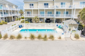 Un hôtel à plusieurs étages doté d’une piscine, de balcons blancs et d’une zone de piscine entourée de clôtures.