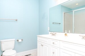 Une salle de bain équipée de toilettes, d’un lavabo avec un miroir et d’une barre d’appui.