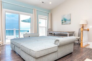 A room with a large bed, a desk, and a view of the ocean.
