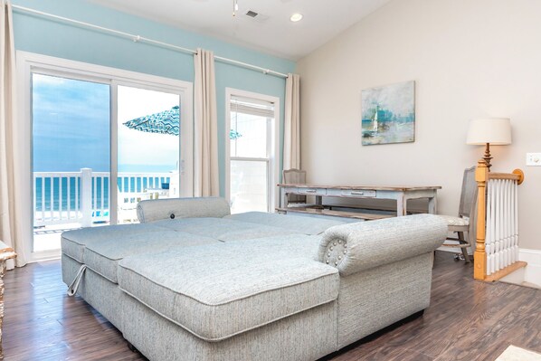 Una habitación con una cama grande, un escritorio y vista al océano.