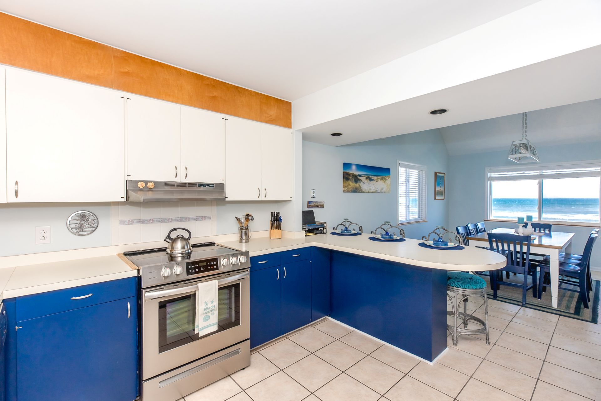 A kitchen with a central island, a dining area with a view, and a beach-themed decor.