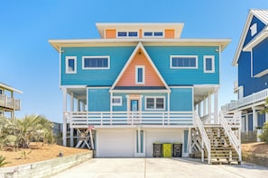 A multi-story beachfront house with a garage, a balcony, and a staircase leading to the upper levels. - Barefoot Shack - Classic Custom 5BR Oceanfront Home - Great Views from Decks (Surf City)