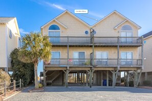 Un hotel frente al mar de varios pisos con balcones, una entrada cubierta y una vista despejada del océano.
