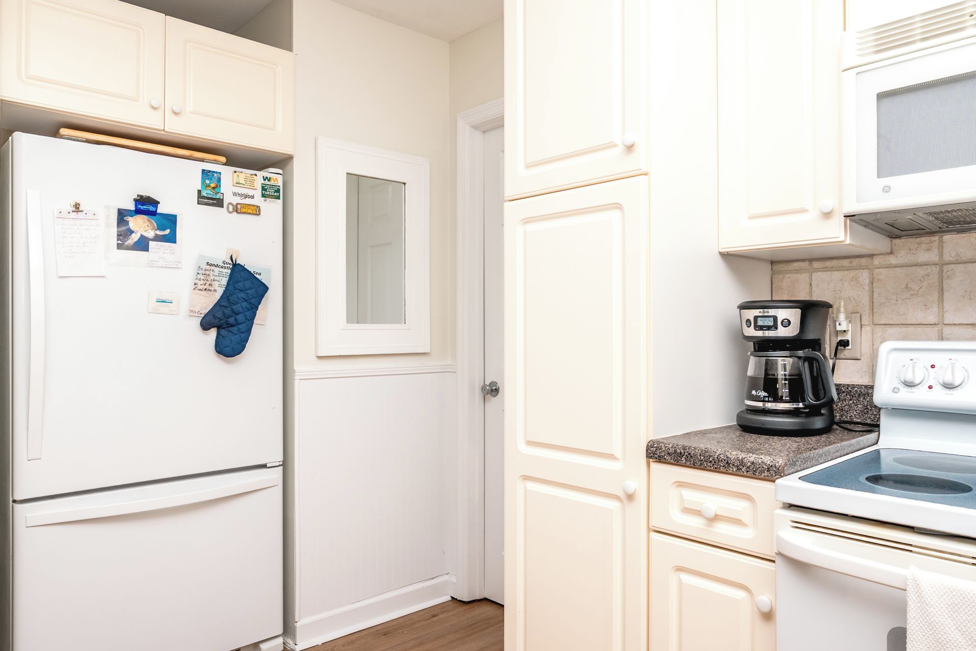 Une cuisine avec un réfrigérateur blanc, une machine à café et une cuisinière.