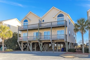 A multi-story wooden building with balconies, a covered entrance, and a clear sky.
