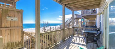 A wooden deck with a view of the ocean, a sign, and outdoor furniture.
