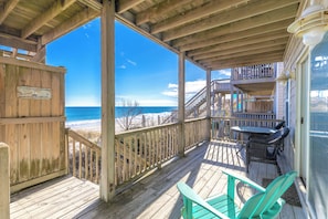 A wooden deck with a view of the ocean, a sign, and outdoor furniture.