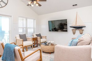 Una sala de estar con sofá, sillones, televisor y ventilador de techo.