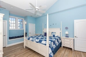 Une chambre à coucher avec un lit à baldaquin, un ventilateur de plafond, une fenêtre et une porte.