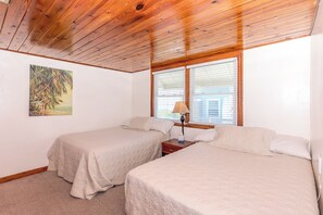 Un dormitorio con dos camas, un cuadro en la pared y una ventana con persianas.