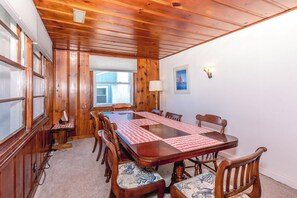 A wooden-paneled room with a large table, chairs, and a window.