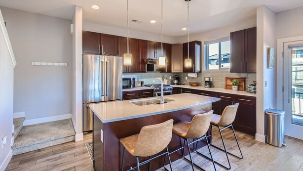 A modern kitchen with a central island, stainless steel appliances, and pendant lighting. - Modern Townhouse - Walkable to Mile High Stadium - Rooftop Views with Firepit (Denver)