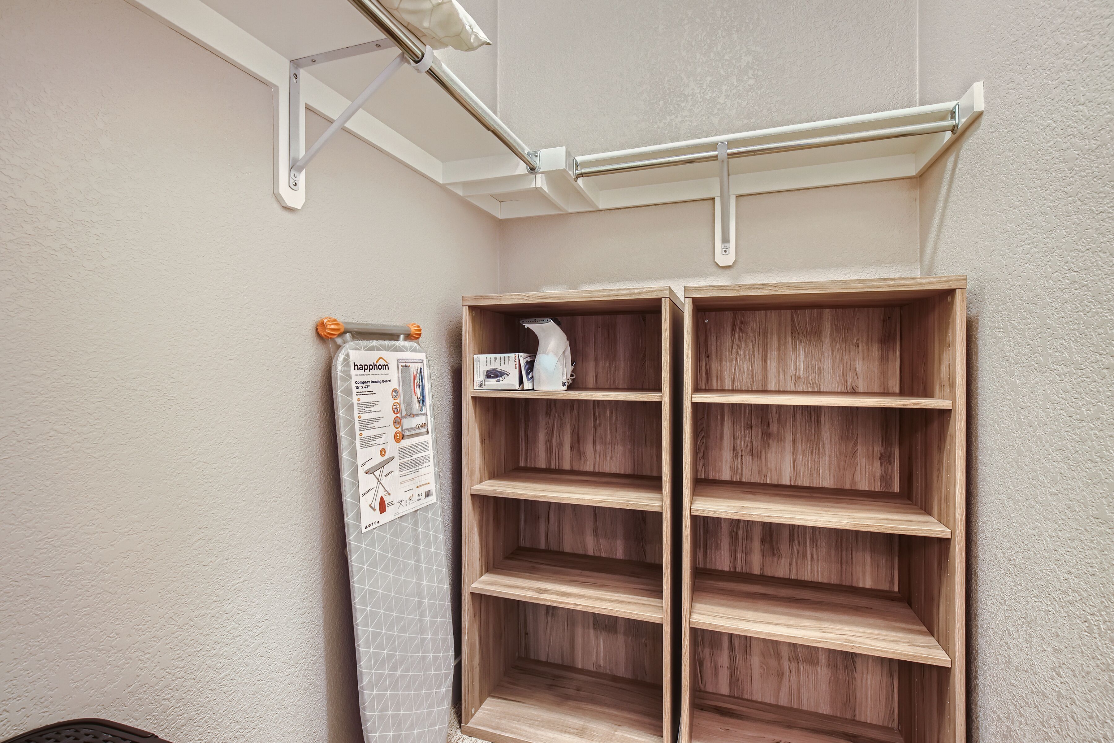 A corner with a wooden shelving unit, a hanging laundry rack, and a metal bracket.