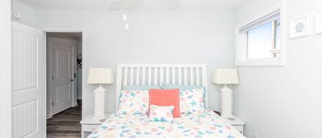 Een slaapkamer met een bed, twee nachtkastjes, een plafondventilator en een raam.