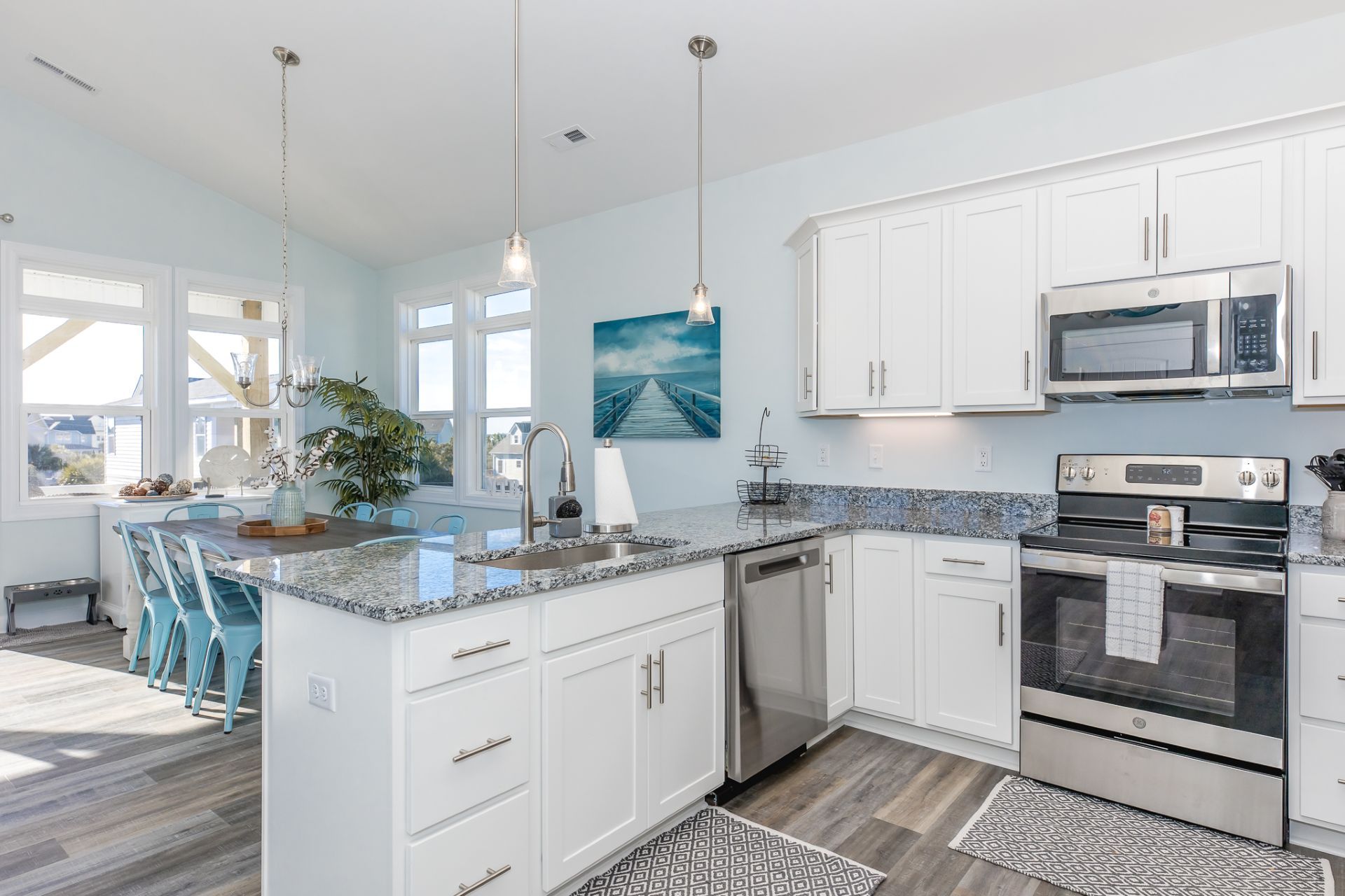 A modern kitchen with white cabinets, stainless steel appliances, and a granite countertop.