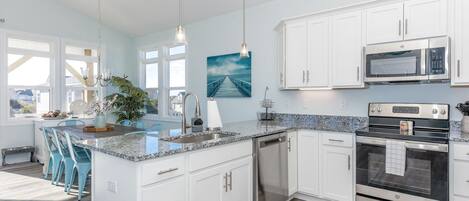 A modern kitchen with white cabinets, stainless steel appliances, and a granite countertop.