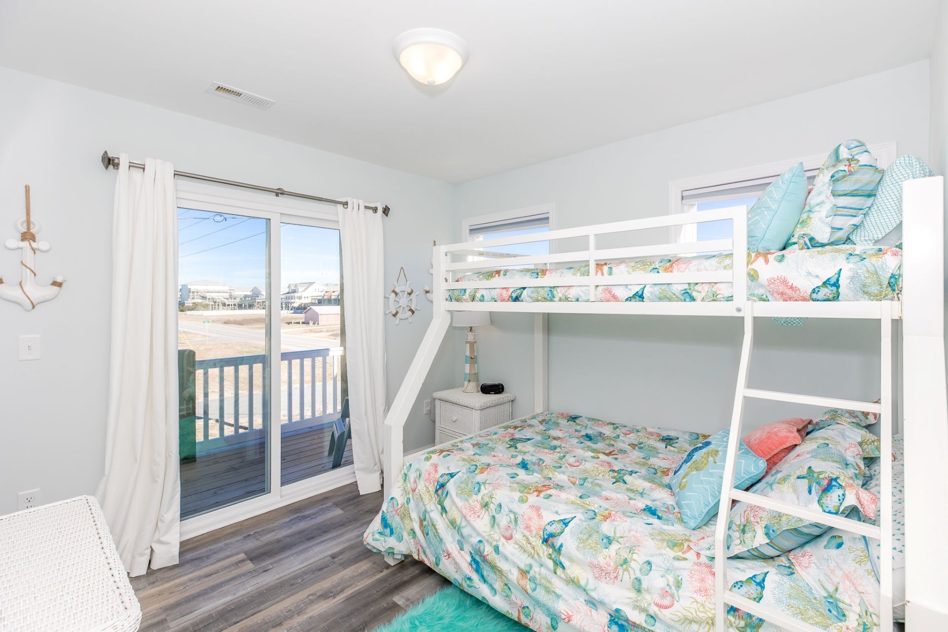 A bedroom with a bunk bed, a desk, and a view of the outside.