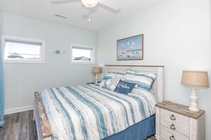 Una camera da letto con un letto, due comodini, una ventola a soffitto e un quadro al muro.