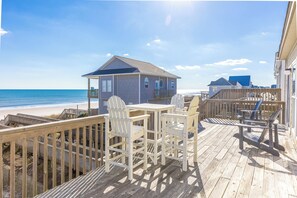 Una terrazza in legno con posti a sedere all'aperto, con vista sulla spiaggia e sull'oceano.