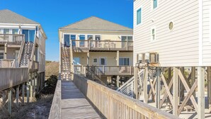Une promenade en bois relie deux bâtiments situés en bord de mer et dotés de balcons.