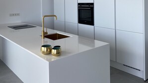 A modern kitchen with a central island, built-in oven, and recessed lighting.